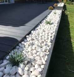 some white rocks and plants in the middle of a garden area with grass on either side