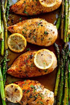 chicken with lemons and asparagus on a baking sheet