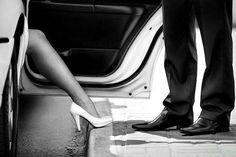 a man and woman standing next to each other in front of a car with the door open