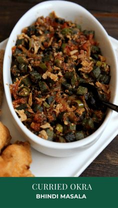 a white bowl filled with food on top of a plate next to some fried vegetables