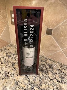 a bottle of wine in a box on a marble counter top with a tile wall behind it