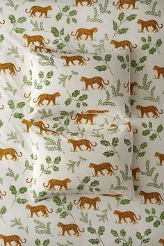 the bedding is decorated with orange and green leopards on white sheeting, along with matching pillow cases