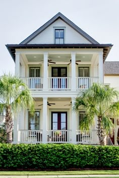 a large white house with palm trees in front