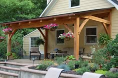 an outdoor covered patio area with chairs and flowers in the foreground, next to a house