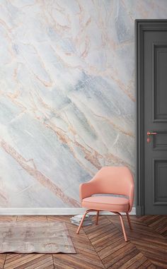 a pink chair sitting in front of a wall with marble design on it's walls