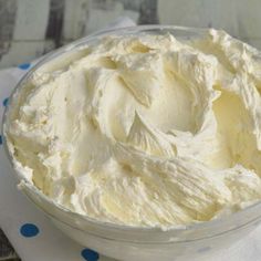 a bowl filled with whipped cream sitting on top of a blue and white polka dot table cloth