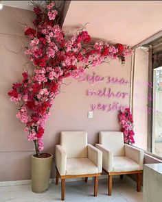 two white chairs sitting in front of a pink wall