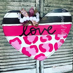 a heart shaped sign with the word love painted on it's side and pink leopard print