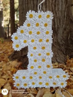 a number one made out of daisies sitting on leaves in front of a tree