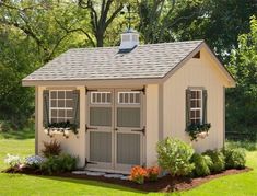 a small shed with two windows and shutters on the roof is shown in front of some trees