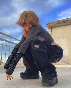 a woman kneeling down on the ground with her hand in her pockets and wearing black boots