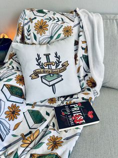 a pillow and some books on a couch next to a blanket with the logo of an organization