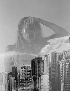 a black and white photo of a woman in front of a city with skyscrapers