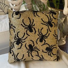 a black and gold spider pillow sitting on top of a bed next to a plant