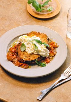 a white plate topped with food on top of a wooden table next to silverware