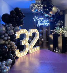 a room filled with balloons and lights next to a number 32 sign that reads happy birthday