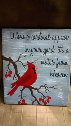 a red cardinal sitting on top of a tree branch next to a sign that says when a cardinal appears in your yard, it's a visitor from heaven