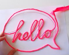 someone is making a neon sign with the word hello written in a speech bubble on paper