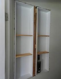 an unfinished closet with two open shelves in the middle and one closed door on the other side