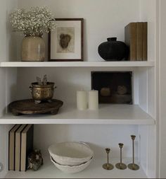 a white shelf filled with books and vases on top of it's shelves