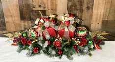 an arrangement of christmas decorations on a white tablecloth with wood planks in the background