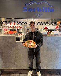 a man standing in front of a counter holding a plate with some food on it