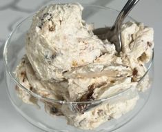 a glass bowl filled with ice cream on top of a white countertop next to a metal spoon