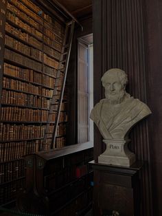 a busturine in the corner of a room with bookshelves