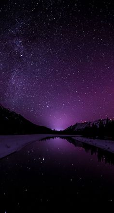 the night sky is filled with stars and purple hues as it reflects in water