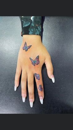 a woman's hand with tattoos on it and three butterflies tattooed on the wrist