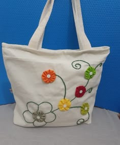 a white bag with flowers on it is sitting on a table next to a blue wall