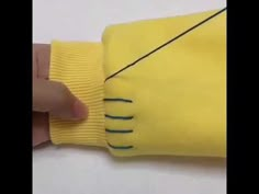 someone is cutting the end of a yellow glove with a black line on it's side