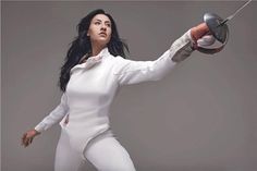 a woman in white jumpsuit holding a frying pan with one arm and two hands