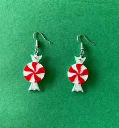 red and white lollipop earrings on green background