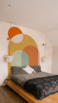 a large bed sitting on top of a wooden floor next to a wall with circles painted on it