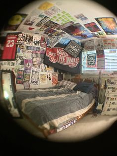 a bed sitting under a mirror covered in pictures and stickers on the wall next to a window