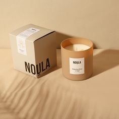 a candle sitting on top of a bed next to a box with nola written on it