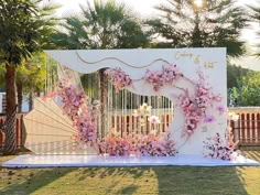 a decorated stage with pink flowers and an umbrella for a wedding or special event in the garden