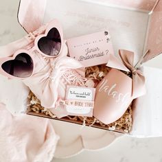 a pink box filled with sunglasses and some other items next to a pair of heart - shaped sunglasses