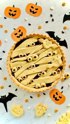 a pumpkin pie with googly eyes and bats on the top is surrounded by halloween decorations