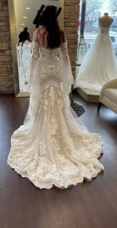 a woman in a wedding dress looking at herself in the mirror