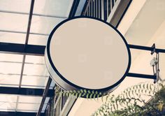 a round sign hanging from the side of a building next to a green plant in front of it