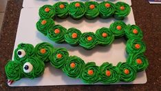 two cupcakes shaped like the letter e on top of a white board with green icing and orange eyes