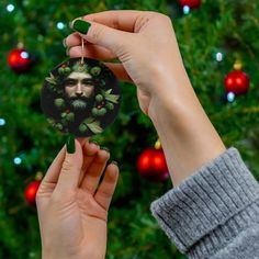 a hand holding a christmas ornament with a man's face on it