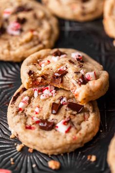 chocolate chip cookies with candy canes and crushed pepper on a black plate in front of other cookies