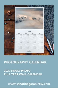 a desk with a calendar, pen and pencils on it that says photography calendar 2021 single photo full year wall calendar