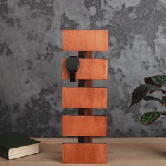 a wooden stand with a watch on it next to a potted plant and book