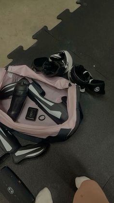 a pink and black bag sitting on top of a floor next to some pairs of shoes