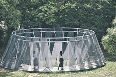 two people are standing in the middle of a round metal structure with mesh covering it