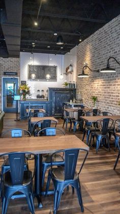 an empty restaurant with wooden tables and blue chairs